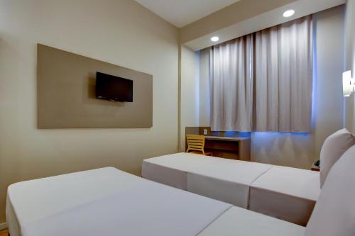 a room with two beds and a desk and a television at Transamerica Fit Rondonopolis in Rondonópolis