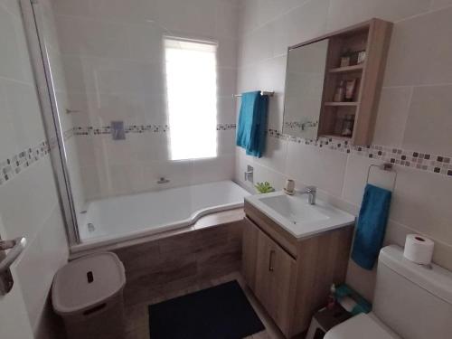 a bathroom with a tub and a sink and a toilet at C-Side Apartment Hibberdene in Hibberdene