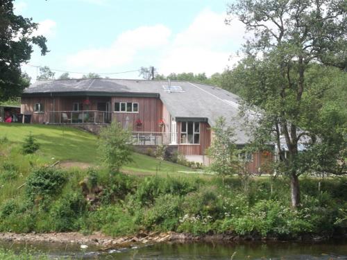 una casa en una colina junto a un río en Black Burn Lodge B & B, en Newcastleton