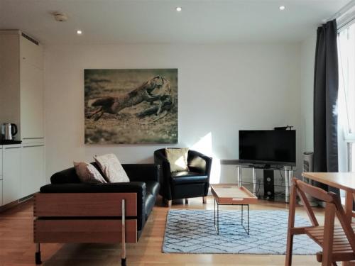 uma sala de estar com um sofá e uma televisão em Still Life St Paul's Executive em Londres