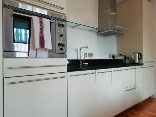 a kitchen with white cabinets and a microwave at Still Life St Paul's Executive in London