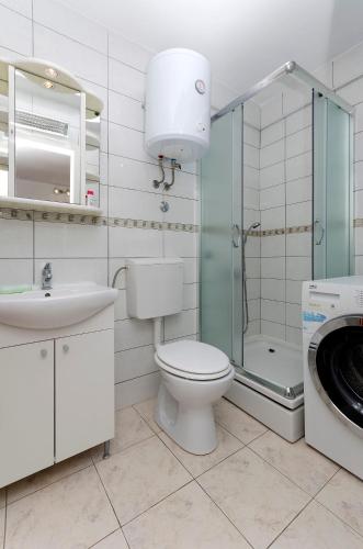 a bathroom with a toilet and a sink and a washing machine at Apartments Mila II in Tribunj