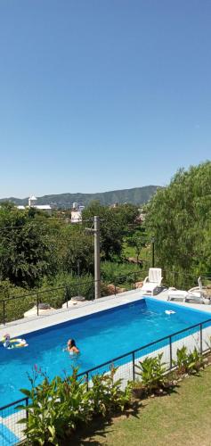 een persoon die zwemt in een groot blauw zwembad bij Cabañas Casitas De Emma in Villa Carlos Paz