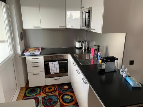 a kitchen with white cabinets and a black counter top at Köln Deutz/Messe, Lanxess Arena in Cologne