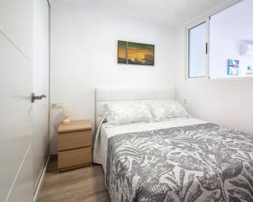 a white bedroom with a bed and a window at virginia-48-2 in Benidorm