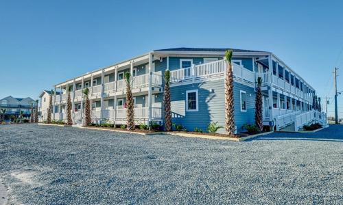 un edificio blu e bianco con palme di fronte di Loggerhead Inn and Suites a Surf City