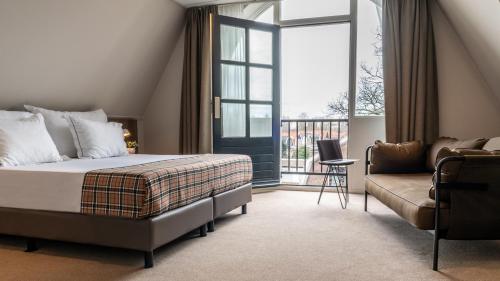 a bedroom with a bed and a couch and a window at Hotel De Koepoort in Enkhuizen