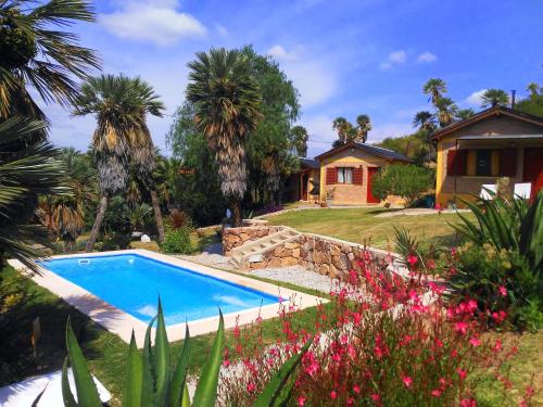 una piscina frente a una casa con flores en Palmares al cerro en Capilla del Monte