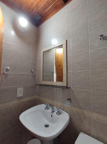 a bathroom with a sink and a mirror and a toilet at Posada Costa del Sol in Colón