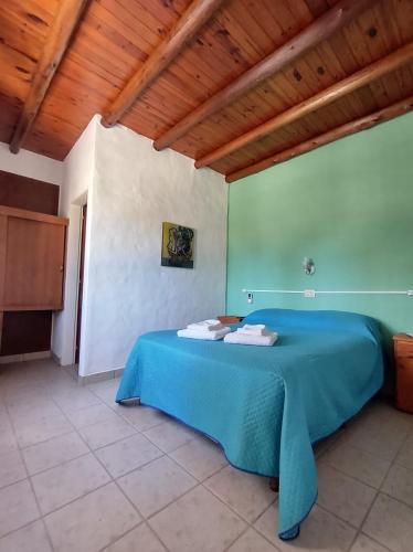 a blue bed in a room with a wooden ceiling at Posada Costa del Sol in Colón