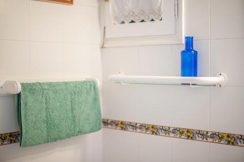 a bathroom with a green towel and a blue bottle at El Faro 8 in Cala'n Bosch
