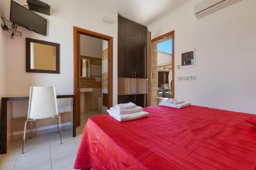 リド・マリーニにあるLido Marini Roomsのベッドルーム1室(赤いベッド1台、タオル付)