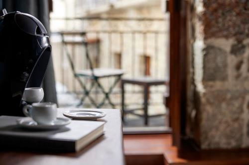 a book and a cup on a table next to a window at Spa Guest House by White Hills in the Heart of Arachova in Arachova