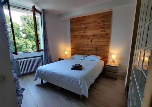 a bedroom with a white bed with a wooden wall at Appartement spacieux centre Aix les Bains in Aix-les-Bains