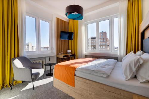 a bedroom with a bed and a chair and windows at Bed & Breakfast Sky City Center in Zagreb