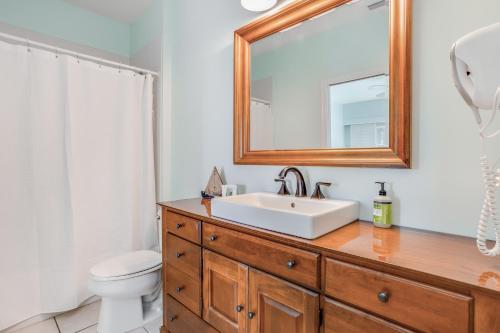a bathroom with a sink and a toilet and a mirror at Sunshine on My Shoulders in Marco Island