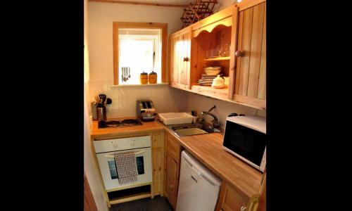 una pequeña cocina con armarios de madera y fregadero en An Carraig Log Cabin en Strathyre