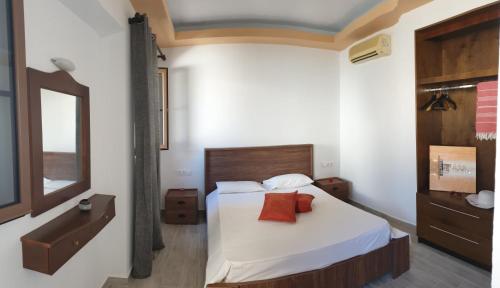 a bedroom with a bed with white sheets and red pillows at Lindos Center Studios in Líndos