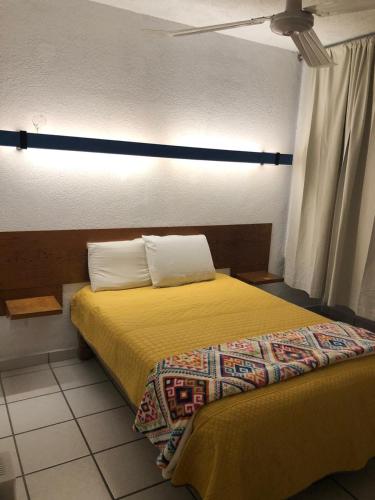 a bedroom with a bed with yellow sheets and pillows at Hotel Vagabundo Puerto Vallarta in Puerto Vallarta