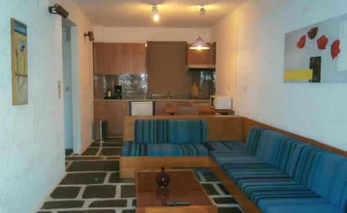 a living room with blue couches and a kitchen at Apollonia Hotel Apartments in Varkiza