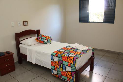 a bedroom with a bed with a colorful blanket on it at Grandes Lagos Park Hotel in Jales