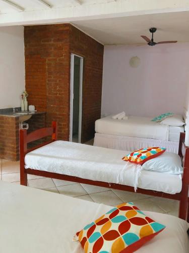 a room with three beds and a kitchen with a table at Nova Aldeia Buzios in Búzios