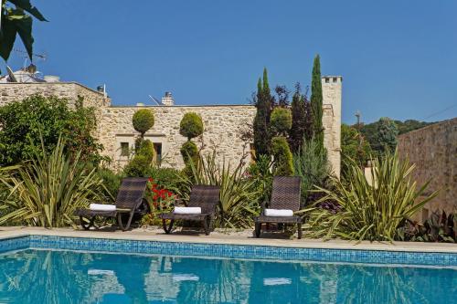 a couple of chairs sitting next to a swimming pool at Arcus Suites in Argyroupolis