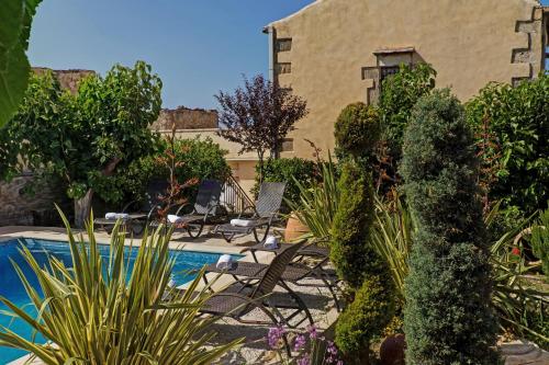 a garden with chairs and plants next to a swimming pool at Arcus Suites in Argyroupolis