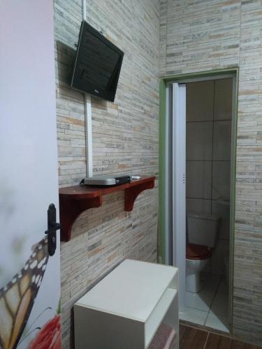 a bathroom with a toilet and a television on a wall at Pousada Encanto e Magia in São Thomé das Letras
