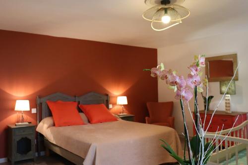 a bedroom with a bed with red walls and orange pillows at Maison D'hôtes Sainte-Marie in Mirande