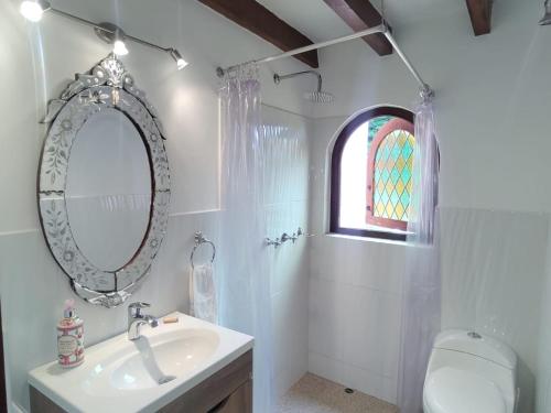 baño con lavabo, espejo y ventana en Hacienda El Pinar del Viento, en Villa de Leyva