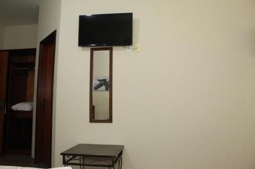 a flat screen tv on a wall with a mirror at Grandes Lagos Park Hotel in Jales