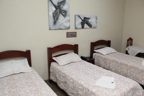 a room with two beds and two paintings on the wall at Grandes Lagos Park Hotel in Jales