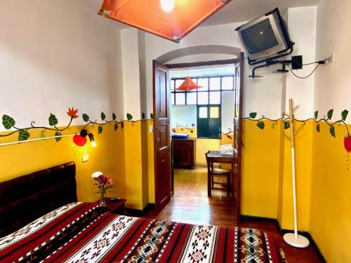 a room with a bed and a tv in a room at Hostal Riviera Sucre in Otavalo