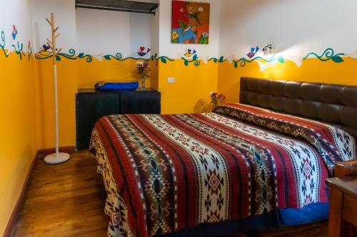 a bedroom with a bed with a blanket on it at Hostal Riviera Sucre in Otavalo