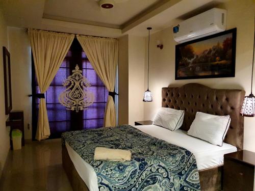 The Millenial Apartments & Suites Bahria Town في روالبندي: غرفة نوم بسرير كبير ونافذة
