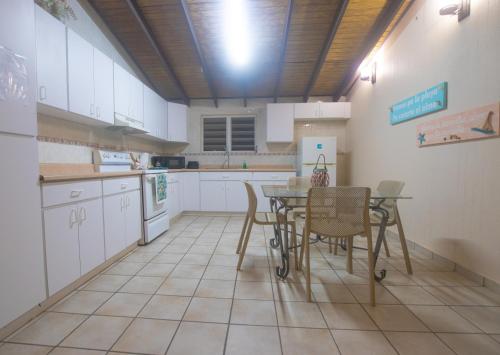 uma cozinha com armários brancos e uma mesa e cadeiras em Chalet Olas del Sol em Punta Santiago