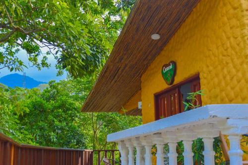 a yellow house with a white railing and a porch at Eco Hostal Kuima in El Zaino