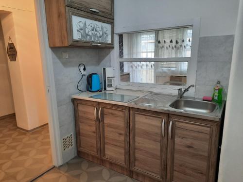 a kitchen with a sink and a window at Eszterlánc Apartman Eger in Eger