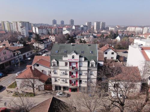 a white building with a green roof in a city at Hotel Garni Rimski in Novi Sad