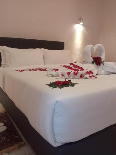 a white bed with roses and two towels on it at Villa Grazia Luxury Hotel in Naivasha