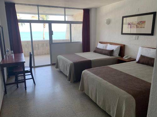 a hotel room with two beds and a desk and a window at Hotel Royalty in Veracruz