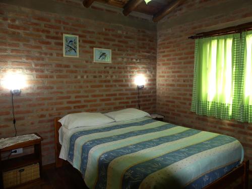 a bedroom with a bed and a brick wall at El Caserio Casas de Campo in Villa Cura Brochero