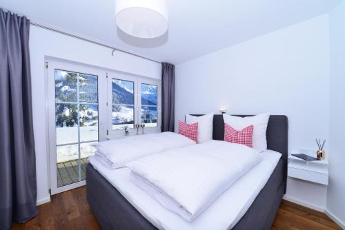 a bedroom with a large bed with a large window at Villa Vanessa Kleinwalsertal in Mittelberg