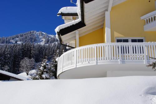 a house with a snow covered balcony with a mountain at Villa Vanessa Kleinwalsertal in Mittelberg