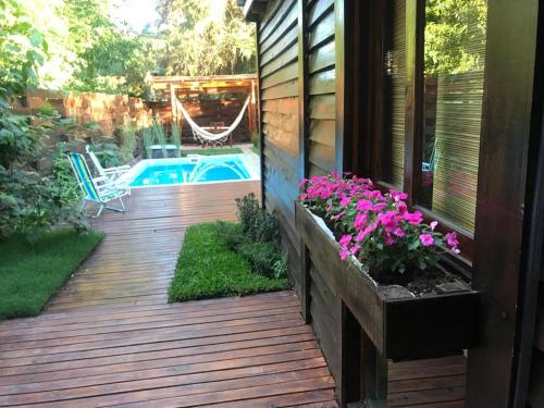 una terraza de madera con piscina y flores en La Casa Del Arbol con pileta privada en Capilla del Señor