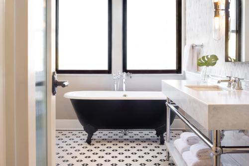 a bathroom with a black tub and a sink at Kimpton Cottonwood Hotel by IHG in Omaha