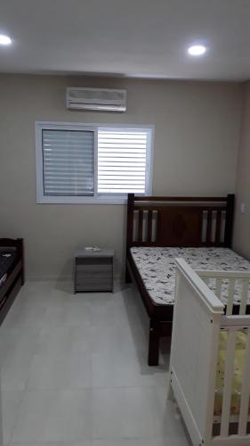 um pequeno quarto com uma cama e uma janela em LINDO SOBRADO GUARUJÁ no Guarujá