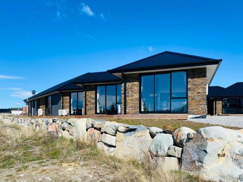 a brick house with a stone wall at Skyblue Tekapo in Lake Tekapo