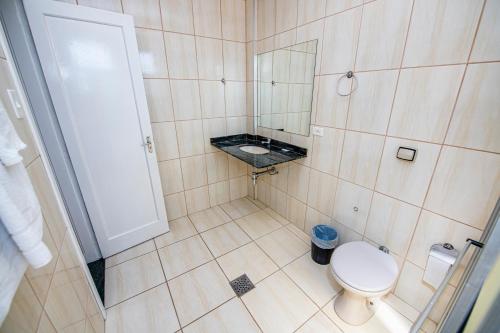 a bathroom with a toilet and a sink and a mirror at Imperador Hotel in Poços de Caldas